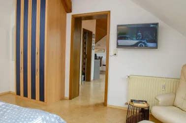 Schlafzimmer mit Schrank, Sessel + TV - Fewo im DG