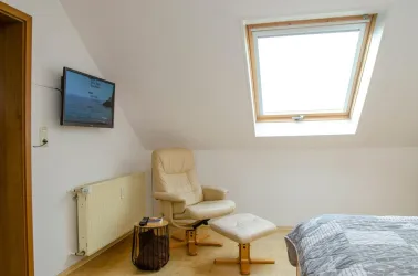 Schlafzimmer mit Schrank, Sessel + TV - Fewo im DG