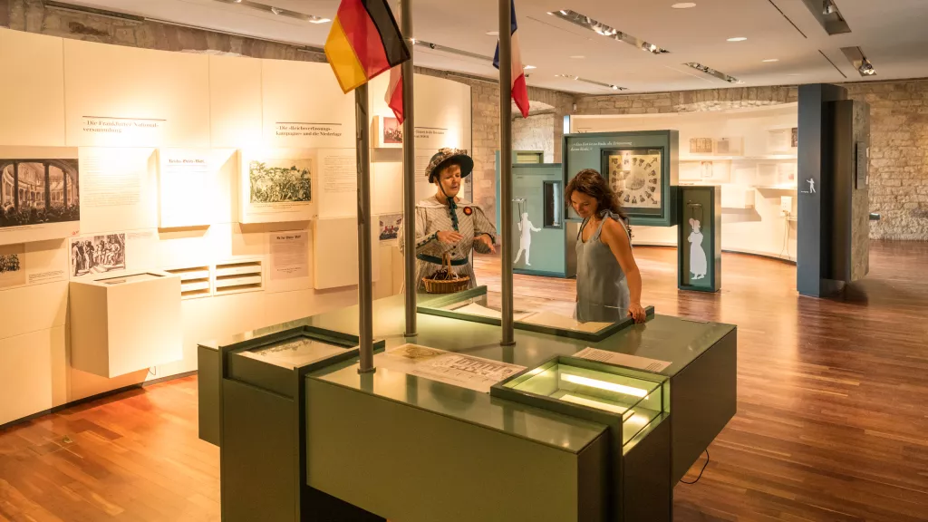 Kostümierte Gästeführerin mit Gast in der Ausstellung im Hambacher Schloss