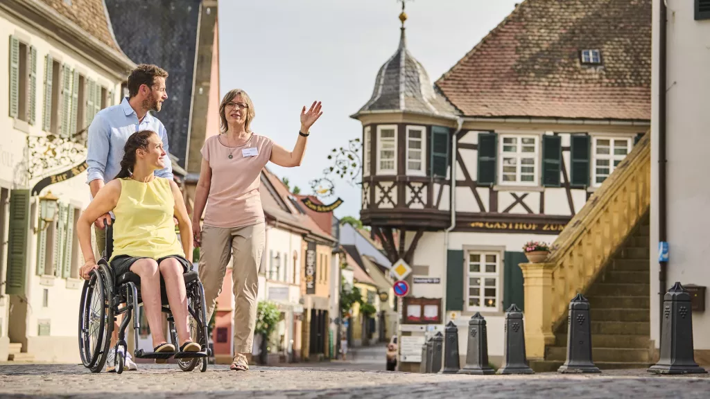 Rollstuhlfahrerin mit Begleiter und Gästeführerin in Deidesheim