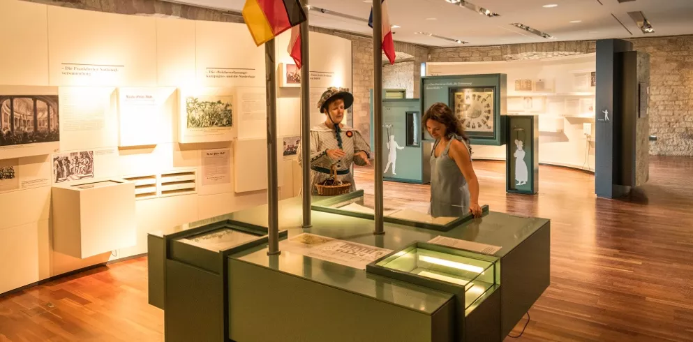 Kostümierte Gästeführerin mit Gast in der Ausstellung im Hambacher Schloss