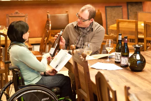 Rollstuhlfahrerin und Partner bei Weinprobe im Weingut von Winning