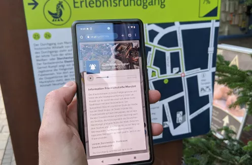 Smartphone vor Tafel des Erlebnisrundgangs